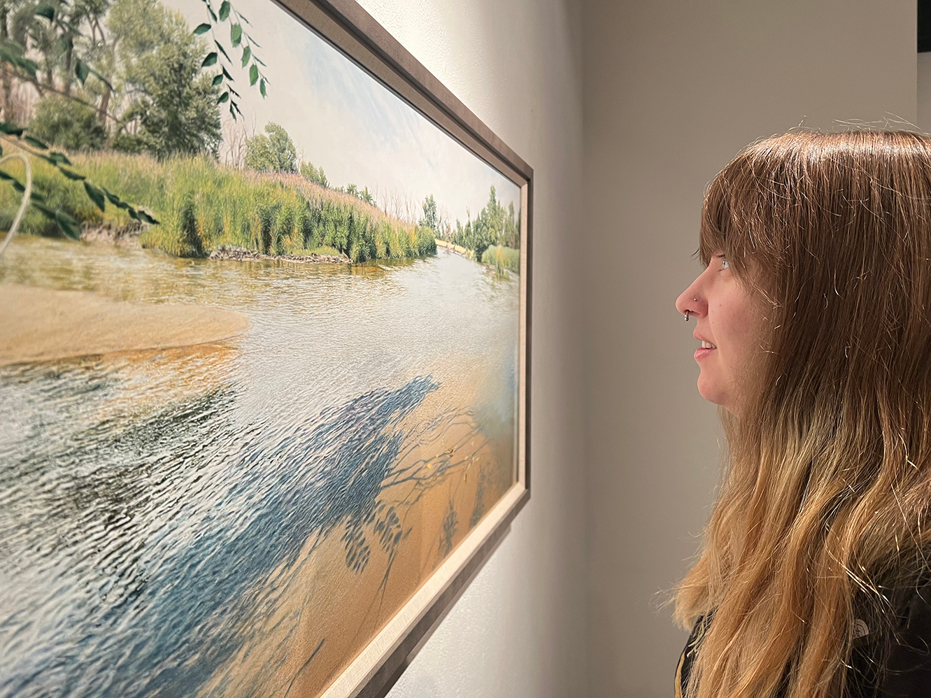 Sydney Badura admires a painting by Fronczak, who worked with abstract paintings for several years before experimenting with realism.